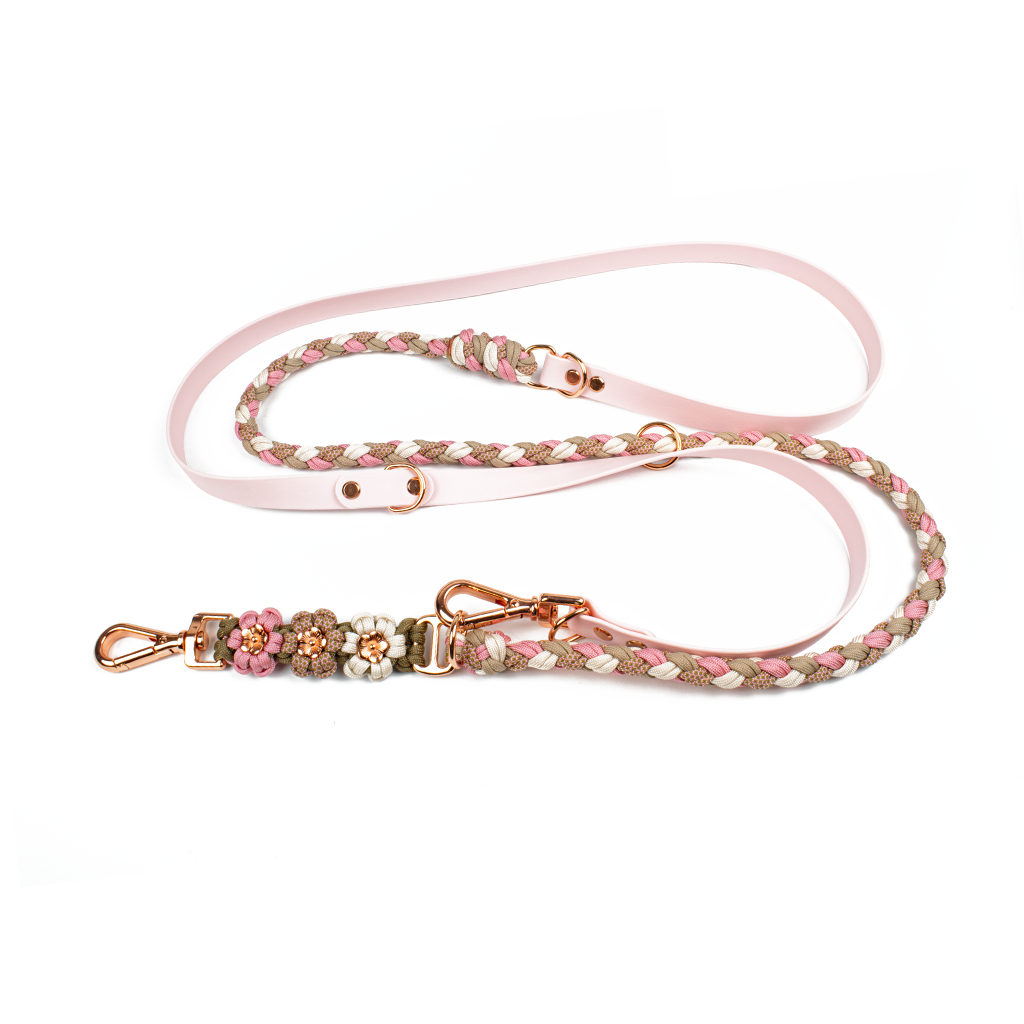 Elegante Hundeleine von Tierluxe aus Biothane und Paracord in Rosa-, Beige- und Weißtönen. Die Leine ist geflochten und mit dekorativen Blumen aus Paracord verziert. Die roségoldenen Karabiner und Schnallen sorgen für ein hochwertiges und stilvolles Aussehen, während die weichen Farben und die Details der Blumen ein charmantes, florales Design bieten.